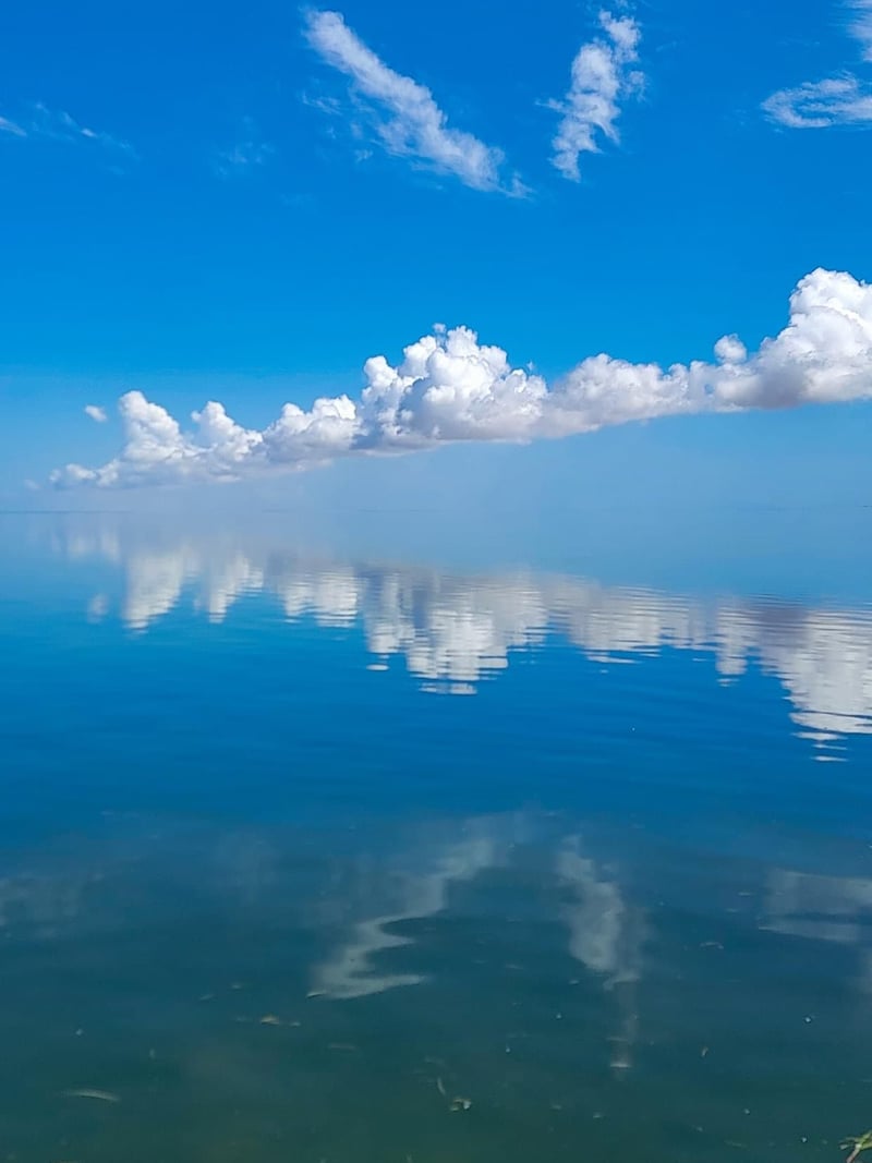 An aerial view of a body of water with clouds reflected in the water.