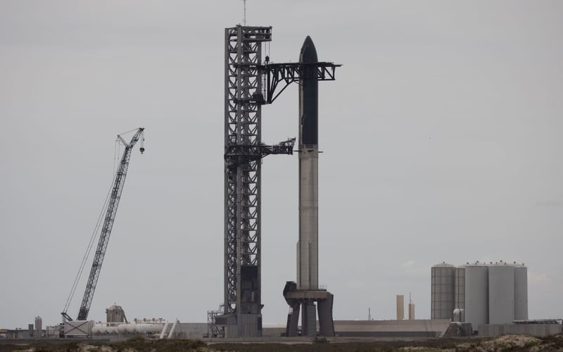 A large rocket is sitting on top of a tower in the middle of a desert.