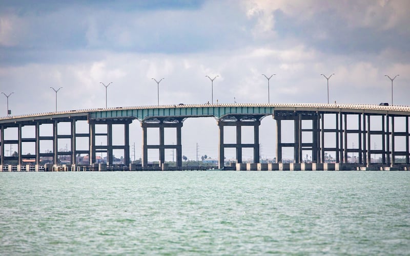 A bridge over a body of water on a cloudy day.
